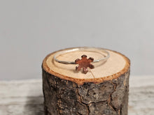 Load image into Gallery viewer, A sterling silver ring with a copper-colored flower-shaped design on a wooden surface.