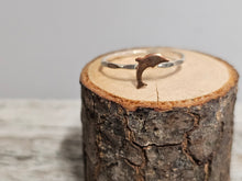 Load image into Gallery viewer, A sterling silver ring with a dolphin design, displayed on a wooden surface.