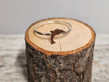 Load image into Gallery viewer, A sterling silver ring with a dolphin design, displayed on a wooden surface.