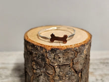 Load image into Gallery viewer, A sterling silver ring with a dog bone design, displayed on a wooden surface.