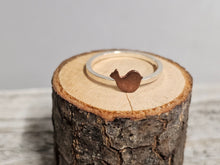 Load image into Gallery viewer, A sterling silver ring with a copper-colored Bird-shaped design on a wooden surface.
