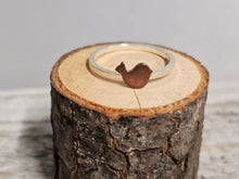 Load image into Gallery viewer, A sterling silver ring with a copper-colored Bird-shaped design on a wooden surface.