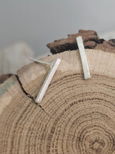 Load image into Gallery viewer, This image features a pair of sterling silver bar earrings, elegantly crafted to capture the essence of simplicity and uniqueness. Each earring is approximately half an inch long, showcasing a clean, minimalist design that highlights the natural beauty of the silver material.