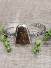 Load image into Gallery viewer, Silver-toned cuff bracelet with triangular brown dinosaur-bone stone and ornate edges