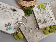 Load image into Gallery viewer, Silver-tone large hoop earrings with bead accents on a jewelry display