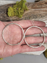 Load image into Gallery viewer, Silver-tone large hoop earrings with bead accents and thin hook backs, held in hand